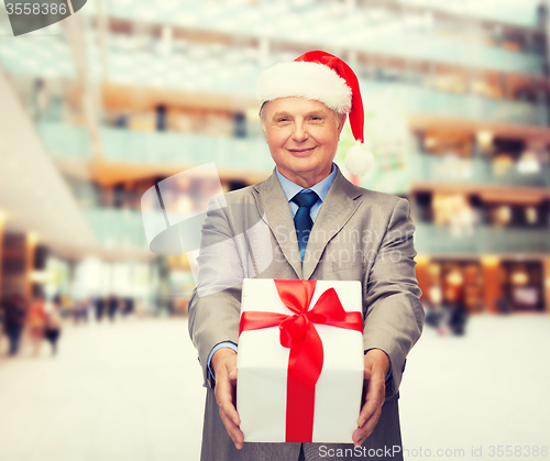 Image of smiling man in suit and santa helper hat with gift