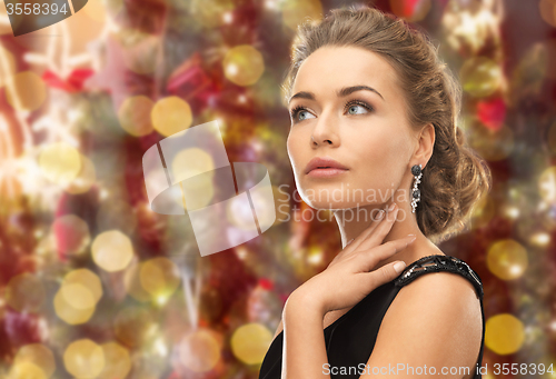 Image of beautiful woman wearing earrings over lights