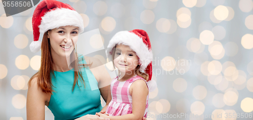 Image of happy mother and little girl in santa hats