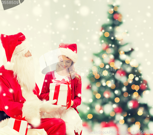 Image of smiling little girl with santa claus and gifts