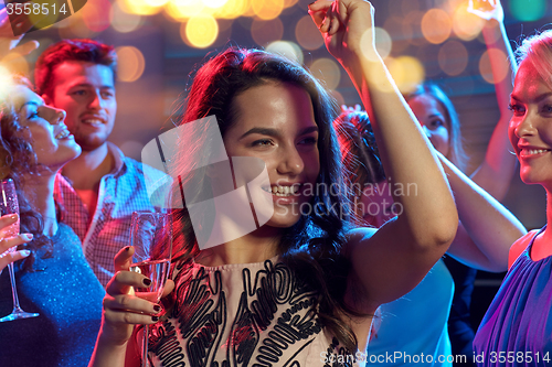 Image of happy friends with champagne dancing at nightclub