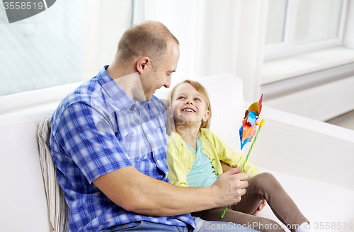 Image of happy father and daughter sitting on sofa at home