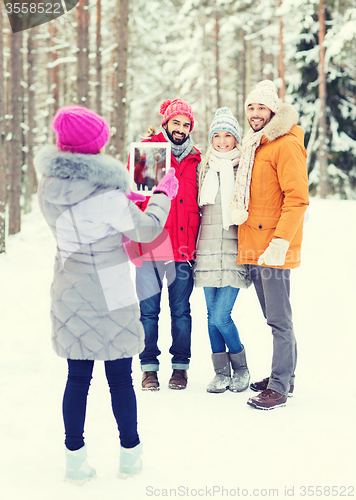 Image of smiling friends with tablet pc in winter forest