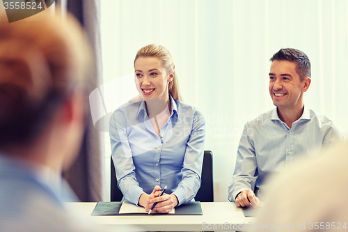 Image of group of smiling businesspeople meeting in office