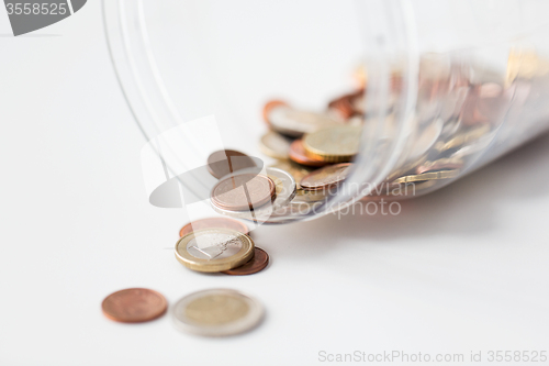 Image of close up of euro coins in open glass jar on table