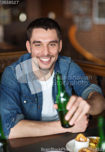 Image of happy young man drinking beer at bar or pub