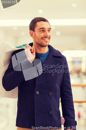 Image of happy young man with shopping bags in mall