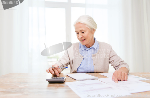 Image of senior woman with papers and calculator at home