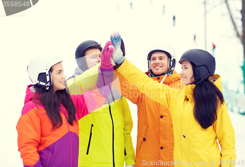 Image of happy friends in helmets making high five