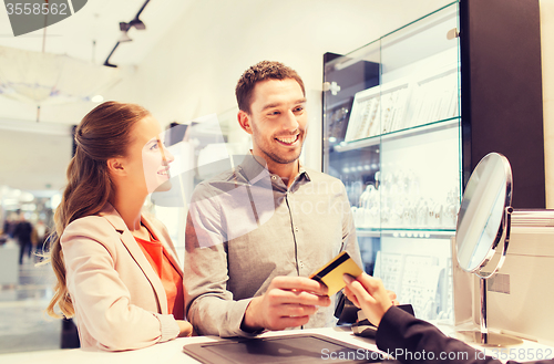 Image of happy couple choosing engagement ring in mall