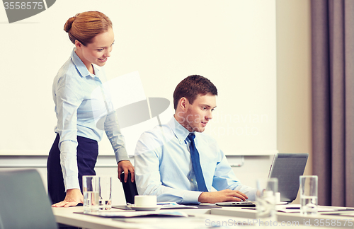 Image of businessman and secretary with laptop in office