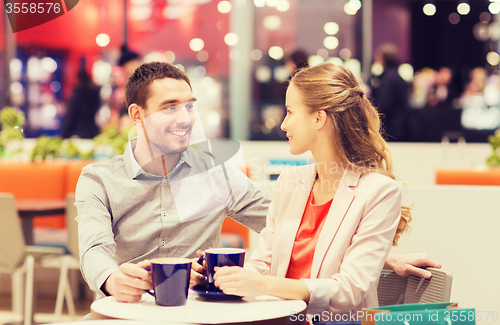 Image of happy couple with shopping bags drinking coffee