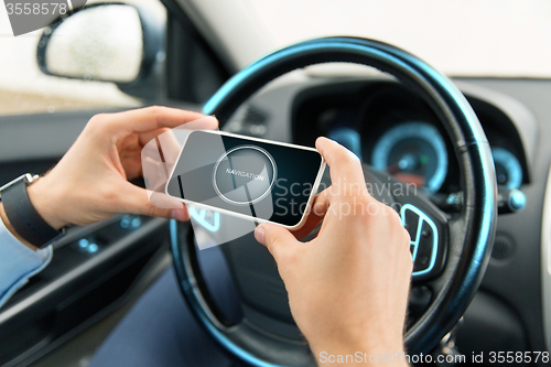 Image of hands with navigator on smartphone in car