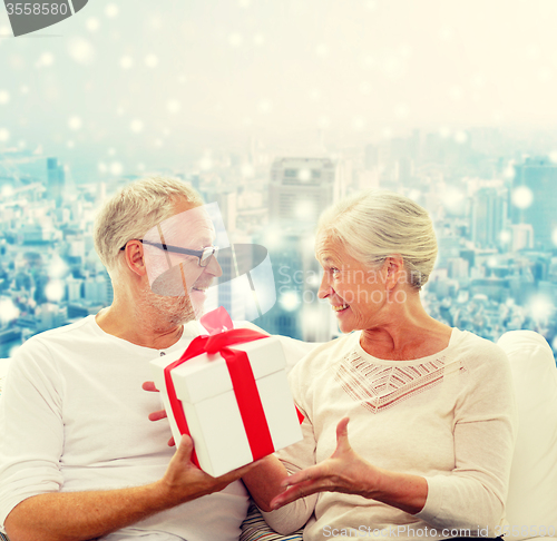 Image of happy senior couple with gift box at home