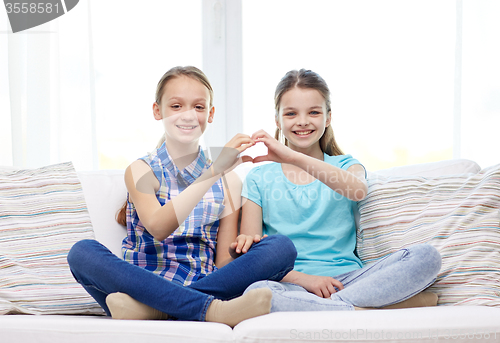 Image of happy little girls showing heart shape hand sign