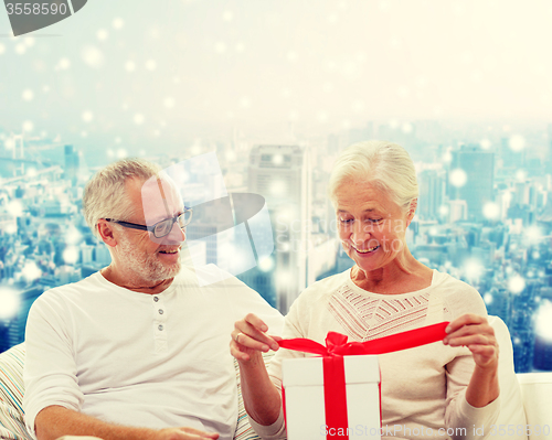 Image of happy senior couple with gift box at home