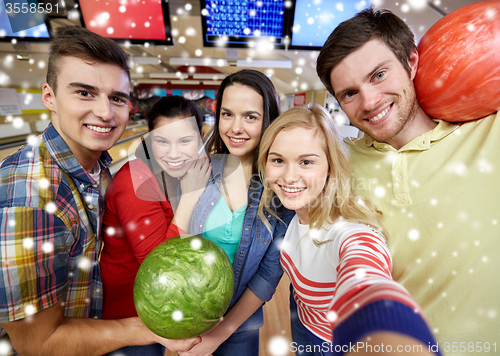 Image of happy friends taking selfie in bowling club