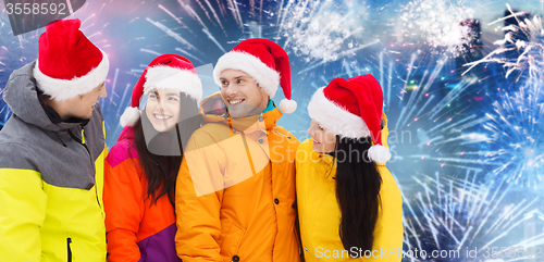 Image of happy friends in santa hats and ski suits outdoors