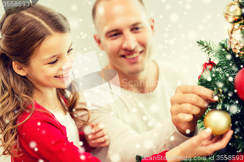 Image of smiling family decorating christmas tree at home