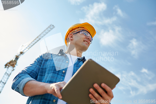 Image of builder in hardhat with tablet pc at construction