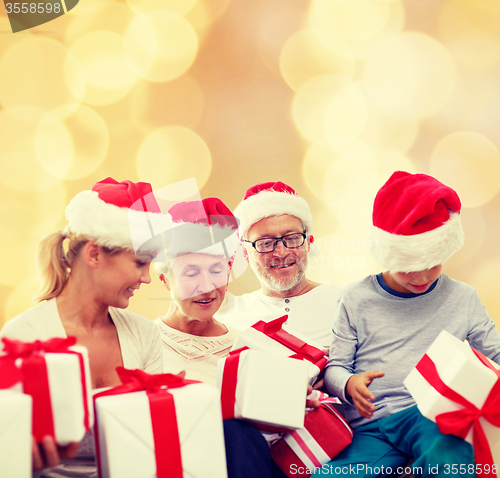 Image of happy family in santa helper hats with gift boxes