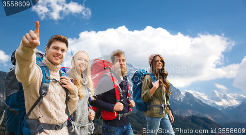 Image of happy friends with backpacks hiking over mountains