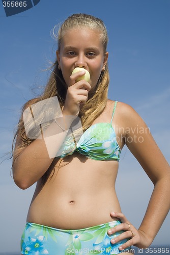 Image of Girl eating apple on the beach