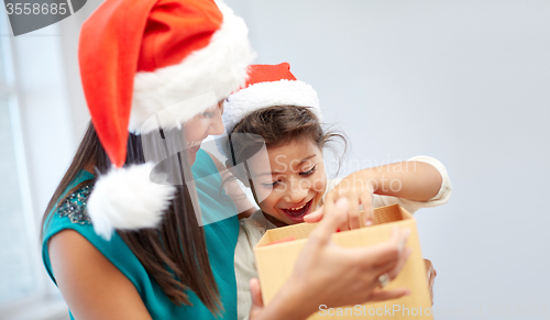 Image of happy mother and child in santa hats with gift box