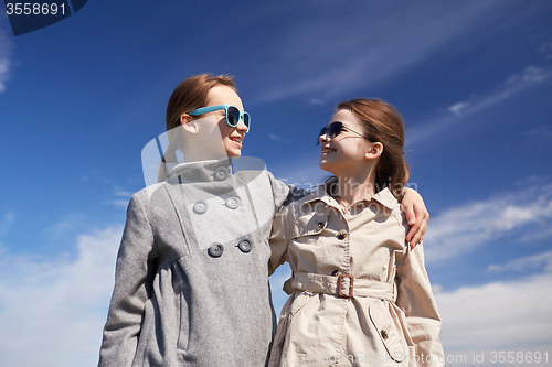 Image of happy little girls hugging and talking outdoors