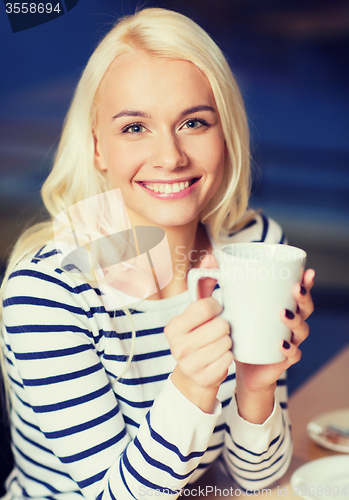 Image of happy young woman drinking tea or coffee