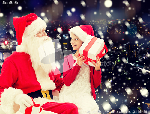 Image of smiling little girl with santa claus and gifts