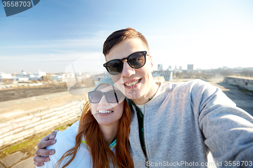 Image of happy teenage couple taking selfie on city street