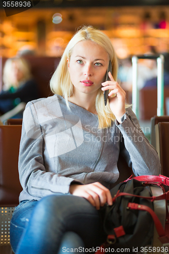 Image of Female traveler using cell phone while waiting.
