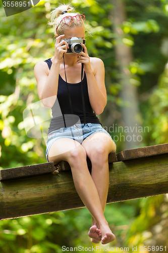 Image of Woman in nature with retro camera.