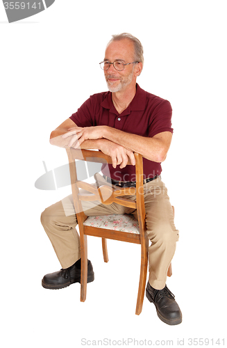 Image of Middle age man sitting backwards on chair.