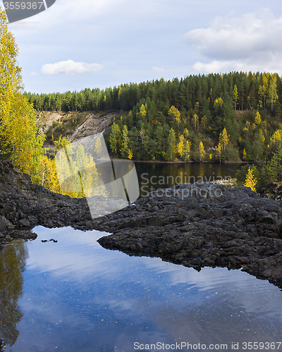 Image of Wild pond on rock in forest in autumn