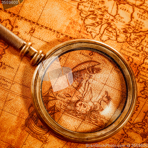 Image of Vintage magnifying glass lies on an ancient world map