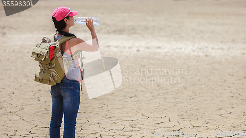 Image of Traveller drinking water from bottle in the desert