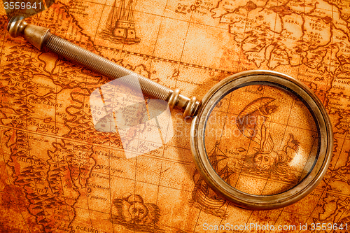 Image of Vintage magnifying glass lies on an ancient world map