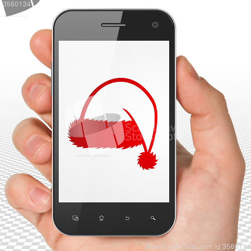 Image of Entertainment, concept: Hand Holding Smartphone with Christmas Hat on display