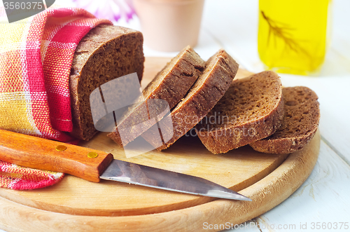 Image of Fresh bread and knife on the wooden board
