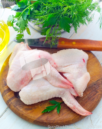 Image of Raw chicken and knife on the wooden board