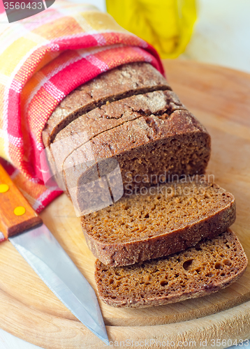 Image of Fresh bread and knife on the wooden board