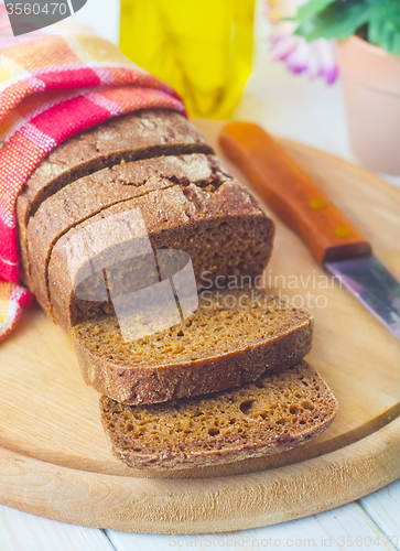 Image of Fresh bread and knife on the wooden board