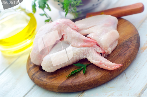 Image of Raw chicken and knife on the wooden board