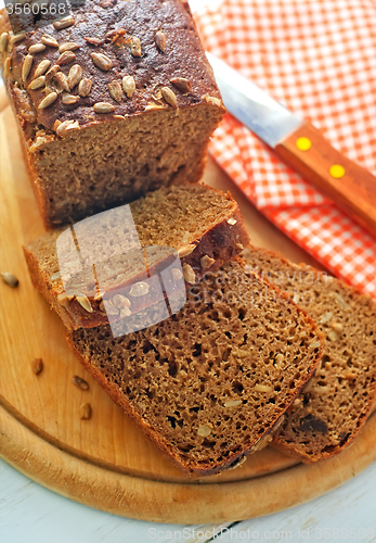 Image of Fresh bread and knife on the wooden board