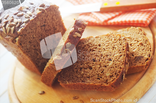 Image of Fresh bread and knife on the wooden board