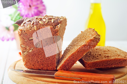 Image of Fresh bread and knife on the wooden board