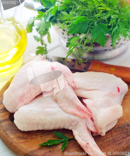 Image of Raw chicken and knife on the wooden board