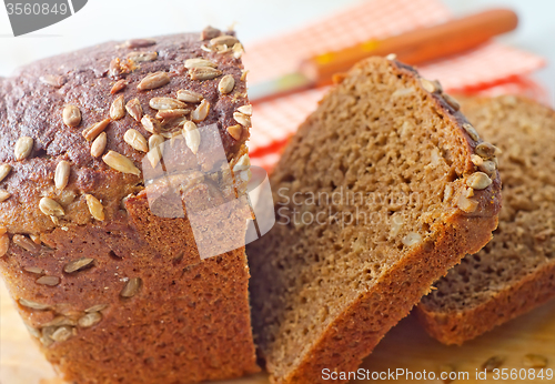 Image of Fresh bread and knife on the wooden board